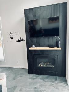 a living room with a fireplace with a flat screen tv at La remontee in LʼAnse-Saint-Jean