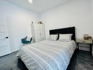 a white bedroom with a bed and a desk at La remontee in LʼAnse-Saint-Jean