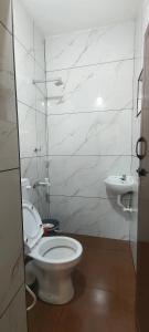 a white bathroom with a toilet and a sink at Beach Bum Varkala in Varkala