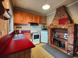 a kitchen with a brick fireplace and a white refrigerator at Justavacation Beachfront Bach in Riverton