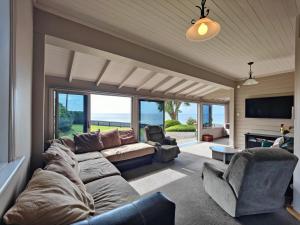 a living room with a couch and chairs and a television at Justavacation Beachfront Bach in Riverton