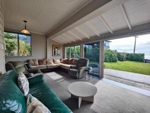 a living room with a couch and a table at Justavacation Beachfront Bach in Riverton
