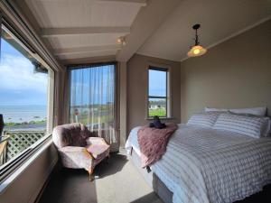 a bedroom with a bed and a chair and a window at Justavacation Beachfront Bach in Riverton