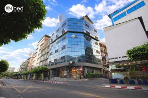 a tall glass building with a clock on it at Mybed Sathorn Hotel in Bangkok