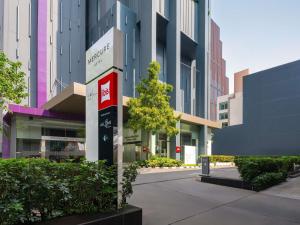 a building with a tree in the middle of a street at ibis Bangkok Siam in Bangkok