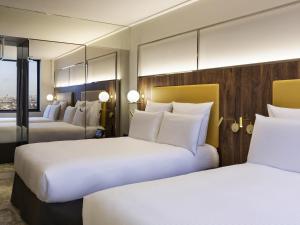 a hotel room with two beds with white pillows at Pullman Paris Montparnasse in Paris