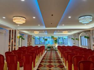 a conference room with red chairs and chandeliers at Hotel Vivaanta in Dhanbād