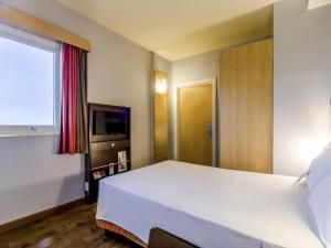 a bedroom with a large white bed and a television at ibis Barretos in Barretos +75 photos