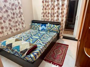 a small bedroom with a bed and curtains and a rug at Revival Villa in Coonoor