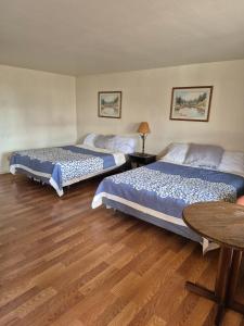 two beds in a room with a wooden floor at 66 Motel in Holbrook