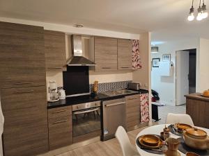 a kitchen with wooden cabinets and a table in a room at Appartement paisible in Quévert