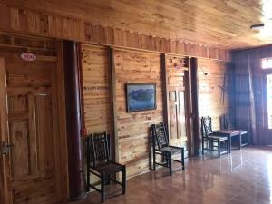 a room with three chairs and a wall with wood at My's Hmong House in Tả Van