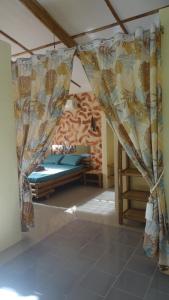 a bedroom with a bed and curtains in a room at ACACIA'S Cottages with Starlink Wifi in Mambajao