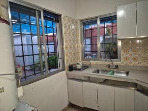 a kitchen with a sink and two windows at Lahogareña in La Cieneguita