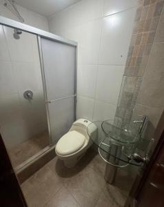 a bathroom with a shower and a toilet and a glass table at Or mini habitación in Cuenca