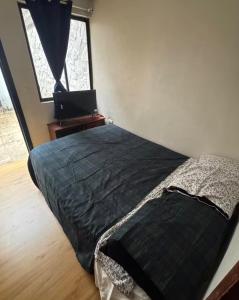 a bedroom with a bed and a window with a laptop at Or mini habitación in Cuenca