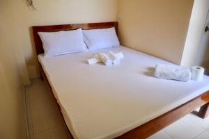 a large white bed with two towels on it at Lake Lovers Stay Hostel in Badian