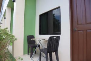 a patio with two chairs and a table next to a door at Lake Lovers Stay Hostel in Badian