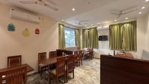 a dining room with green curtains and a table and chairs at Shrileela Beach Resort in Murūd