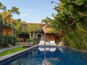 a villa with a swimming pool in front of a house at Penida Green Palm Cottage in Nusa Penida