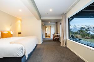 a bedroom with a bed and a large window at Hidden Lodge Queenstown in Queenstown