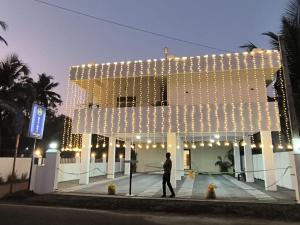 a man walking in front of a building with lights at Marari A R Residency in Mararikulam