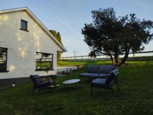 a yard with chairs and a table and a tree at Vakantiehuis 't Leideveld in Maarkedal