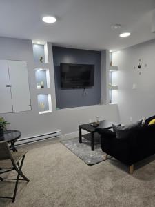 a living room with a couch and a tv on a wall at Basement suite in Winnipeg in Winnipeg