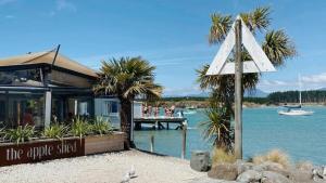 a restaurant on the water with palm trees and a boat at Mapua Village Modern Studio in Mapua
