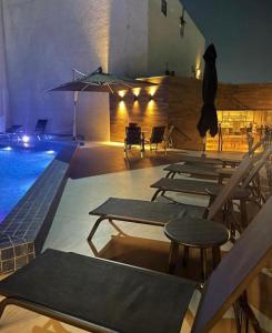 a swimming pool with tables and chairs and an umbrella at Flat Aconchegante Hotel Intercity Manaus in Manaus
