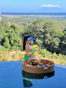 a woman sitting on a floating island in the water at Sumberkima Resort in Pemuteran +70 photos