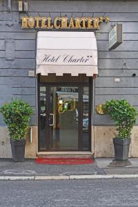 a hotel entrance with two potted plants in front of a building at Hotel Charter in Rome