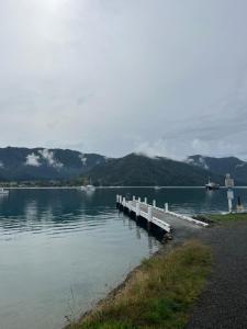 a dock on a lake with mountains in the background at Queen Charlotte Bach in Linkwater