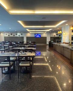 a restaurant with tables and chairs and a bar at Flat Aconchegante Hotel Intercity Manaus in Manaus