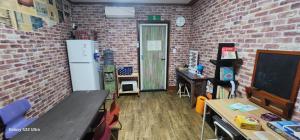 a classroom with a white refrigerator and a brick wall at Jarasum guesthouse in Kap'yŏng-yŏk