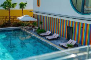 a pool with chairs and an umbrella next to a building at Coast Pearl Hotel in Phú Quốc