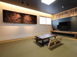a dining room with a table and a large screen tv at 虎屋旅館 in Kotohira