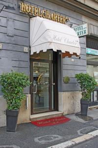 un ingresso dell'hotel con due piante in vaso di fronte a un edificio di Hotel Charter a Roma