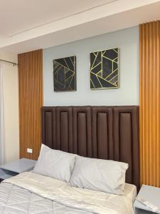 a bed in a bedroom with three pictures on the wall at Primavera Citta Verde in Balulang