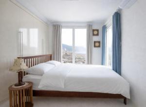 a bedroom with a large white bed with a window at 남해독일마을드레스덴 in Samhwa-dong