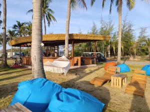 a park with a tent and benches and palm trees at Coast Pearl Hotel in Phú Quốc