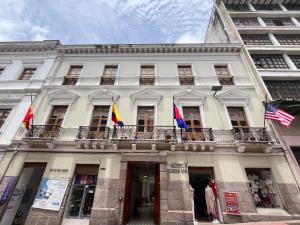 a white building with three flags on a balcony at Rossa Mia Hotel Boutique in Quito