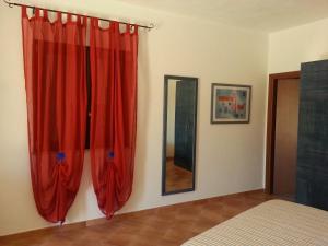 una camera da letto con tende rosse e specchio di La Casetta di Sara a Lampedusa