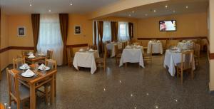 a dining room with white tables and chairs at Pensiunea Floarea de Colt in Nucşoara