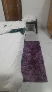 a white bed with a purple rug next to a table at Hotel Prabhawati Palace Near Railway Station and Sri Vishwanath Temple Varanasi in Varanasi +5 photos