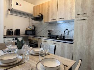 a kitchen with a table with plates and wine glasses at Appartement Cosy Trelazé in Trélazé