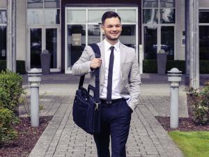 a man in a suit and tie carrying a bag at Mercure Kamen Unna in Kamen