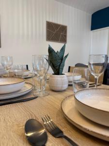 a wooden table with plates and wine glasses on it at Appartement Cosy Trelazé in Trélazé