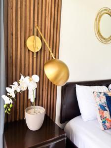 a table with a lamp and flowers on a bed at Suite Palm in Palma