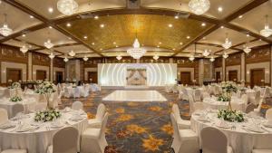 a banquet hall with white tables and chairs and a stage at Danat Al Ain Resort in Al Ain +66 photos